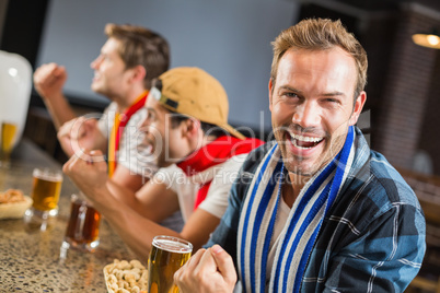 Man looking at camera while other men cheer for the game