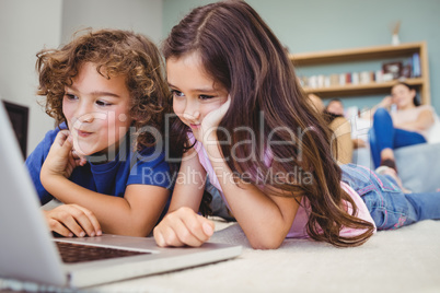 Close-up of siblings looking in laptop at home