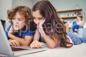 Close-up of siblings looking in laptop at home