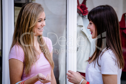 Two beautiful women talking outside a shop