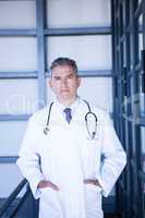 Serious male doctor standing with hands in pocket