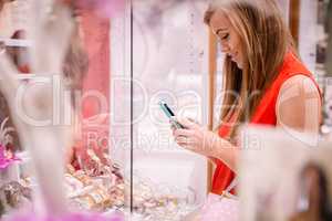 Beautiful woman texting while selecting a wrist watch