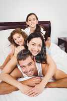 Portrait of cheerful family lying on bed