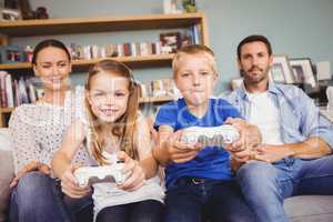 Smiling siblings playing video games with parents