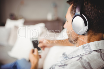 Man using mobile phone while listening music with headphones