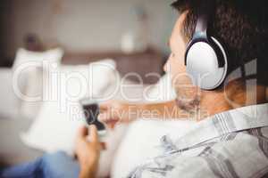Man using mobile phone while listening music with headphones