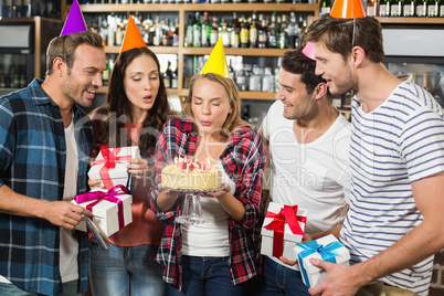 Woman blowing out candles while friends watch