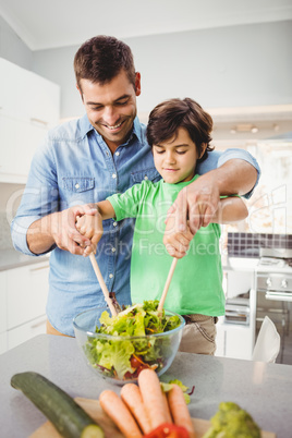 Happy father and son preparing salad