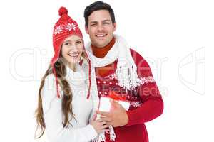 Happy couple with winter clothes holding gift box