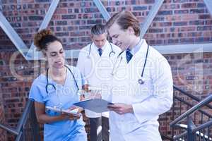 Doctors discussing medical report on staircase