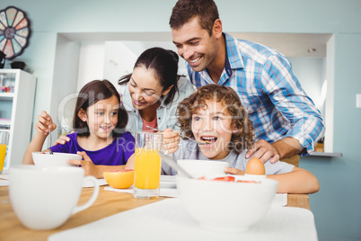 Cheerful man and woman with children during breakfast