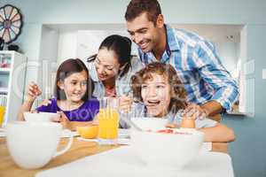 Cheerful man and woman with children during breakfast
