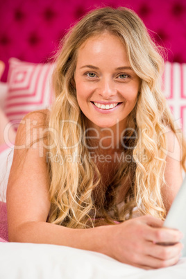 Pretty woman lying on her bed using tablet