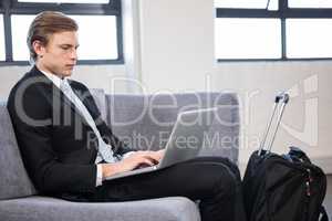 Businessman sitting on sofa and using laptop