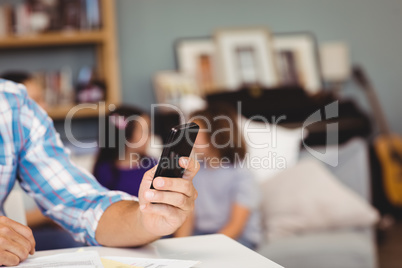 Man using mobile phone while family in background