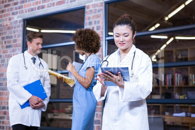 Female doctor using digital tablet near library