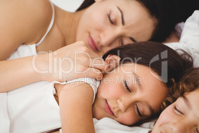 Children sleeping with mother on bed