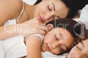 Children sleeping with mother on bed