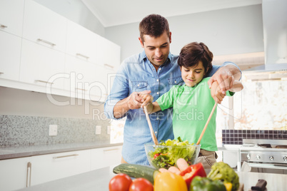 Cheerful father and son preparing salad