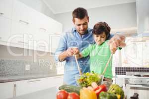 Cheerful father and son preparing salad