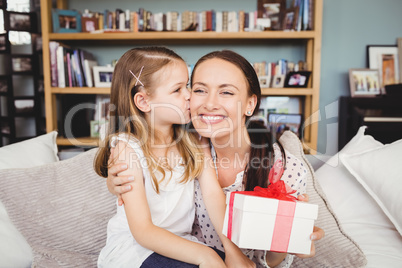 Daughter kissing mother with gift box