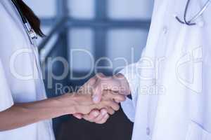Mid section of doctors shaking hands