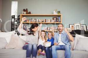 Smiling family with arms raised while watching television