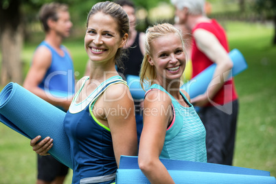 Fit women posing with sports mats back to back