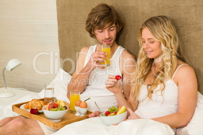 Cute couple having breakfast in bed