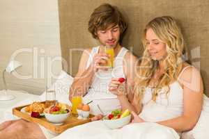 Cute couple having breakfast in bed