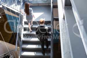Businesspeople climbing staircase in office