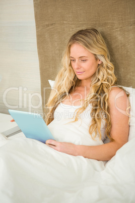 Pretty woman using tablet computer in her bed