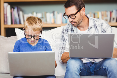 Father and son with eyeglasses while working on laptop