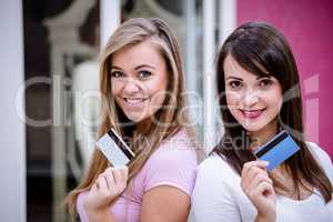 Portrait of happy women showing their credit cards in mall