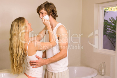 Cute couple playing with shaving foam in the bathroom