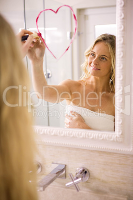 Beautiful blonde drawing big heart on mirror