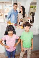 Siblings standing at table with parents preparing fruit juice