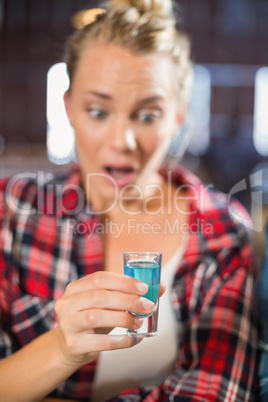 Woman looking at shot glass surprised