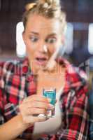 Woman looking at shot glass surprised