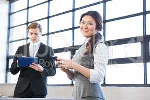 Businessman using digital tablet and businesswoman using mobile