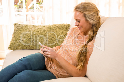 Pretty blonde using smartphone on the couch