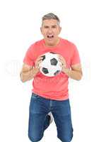Man shouting and holding a soccer ball