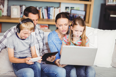 Children using technologies with parents on sofa