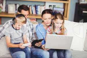 Children using technologies with parents on sofa