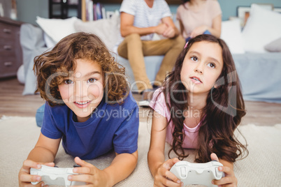 Siblings with playing video game on carpet