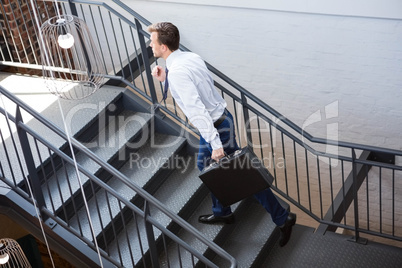 Businessman holding briefcase and climbing staircase