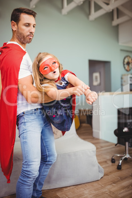 Father holding daughter wearing superhero costume