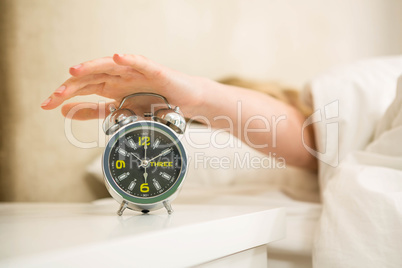 Pretty woman shutting off her alarm clock