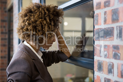 Tired businesswoman leaning on window