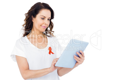 Woman with red aids awareness ribbon using tablet